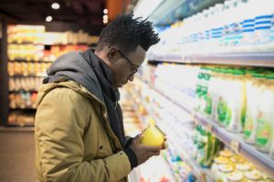 A young man inspects the nutrition label on a jar at a grocery store